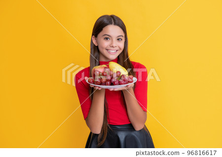 smiling girl hold fresh fruit plate on yellow background smiling girl hold fresh fruit plate on yellow background 96816617
