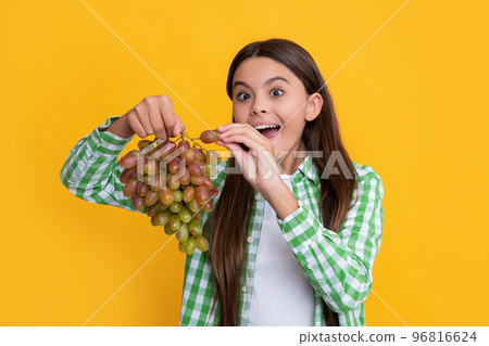 amazed teen girl with grapes bunch on yellow background 96816624