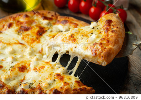 A slice of hot Italian pizza with stretching cheese. Pizza four cheeses with basil. A slice of hot Italian pizza with stretching cheese. Pizza four cheeses with basil. 96816809