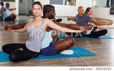 females and males doing stretching workout in pairs females and males doing stretching workout in pairs 96816950