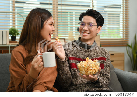 Image of young happy couple with popcorn watching tv at home. Leisure and people concept 96818347