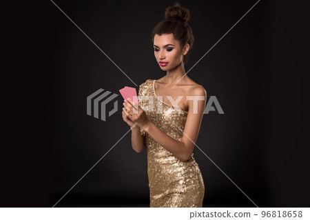 Woman winning - Young woman in a classy gold dress holding two cards, a poker of aces card combination. Emotions 96818658