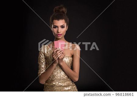 Woman winning - Young woman in a classy gold dress holding two cards, a poker of aces card combination. Emotions Woman winning - Young woman in a classy gold dress holding two cards, a poker of aces card combination. Emotions 96818661