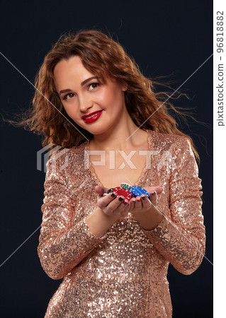 Casino concept. Portrait of young pretty caucasian woman, playing in casino. Roulette, poker chips, cards, wheel, black background Casino concept. Portrait of young pretty caucasian woman, playing in casino. Roulette, poker chips, cards, wheel, black background 96818882