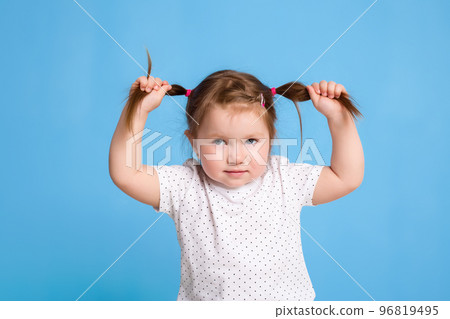 Funny kid in white T-shirt on blue background. Little pretty girl isolated on blue background. Copy space for text. 96819495