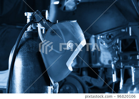Welding equipment in a car repair station, helmet hanging on a gas tank, no people Welding equipment in a car repair station, helmet hanging on a gas tank, no people 96820106