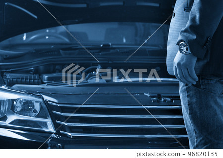Man looking on the engine of a car with open hood 96820135