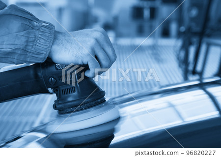 Man using polisher to polish black car body in the workshop 96820227