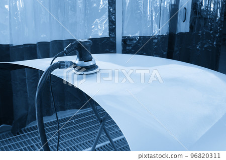 Auto mechanic buffing and polishing car in auto repair shop with orbital polisher, basic layer cleaning 96820311