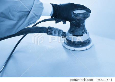 Auto mechanic buffing and polishing car in auto repair shop with orbital polisher, basic layer cleaning 96820321