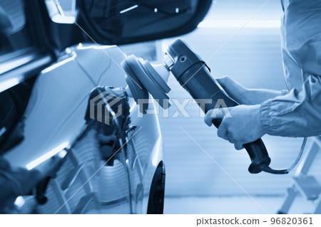 Man using polisher to polish black car body in the workshop Man using polisher to polish black car body in the workshop 96820361