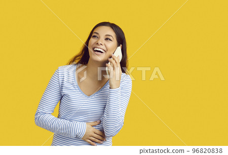 Portrait of excited woman touching her stomach with hand talking on phone isolated on yellow colored background with blank space Portrait of excited woman touching her stomach with hand talking on phone isolated on yellow colored background with blank space 96820838
