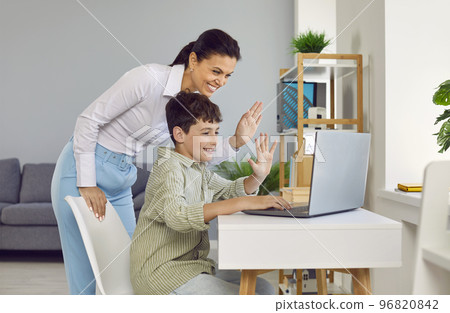 Friendly mom and her preteen son are having online conversation using laptop web camera. 96820842