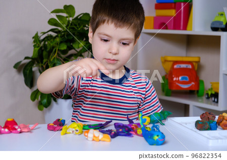 A boy of 4 years old sculpts figures of marine animals from plasticine. A boy of 4 years old sculpts figures of marine animals from plasticine. 96822354
