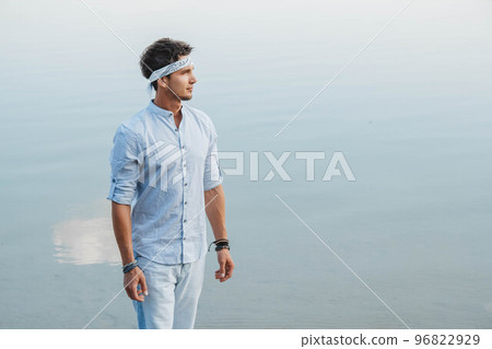 Man handsome dressed in light clothes looks at the water reflex of blue sky. Concept of freedom relaxation. Place for text or advertising 96822929