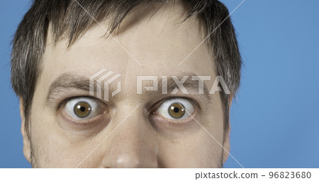 Surprised eyes of a man on a blue background text copy space. Big bulging eyes. To advertise discounts, sales, pawnshops or credit. Surprised eyes of a man on a blue background text copy space. Big bulging eyes. To advertise discounts, sales, pawnshops or credit. 96823680