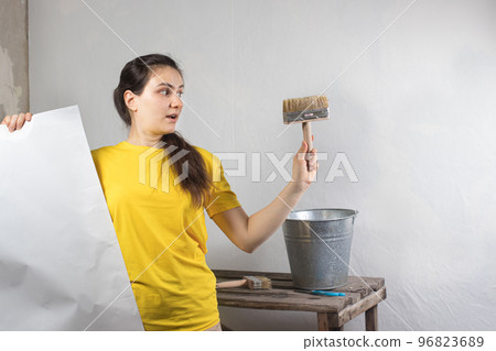 A woman repairman glues white wallpaper on the wall. Repair work, wallpapering. Place for text copy space A woman repairman glues white wallpaper on the wall. Repair work, wallpapering. Place for text copy space 96823689
