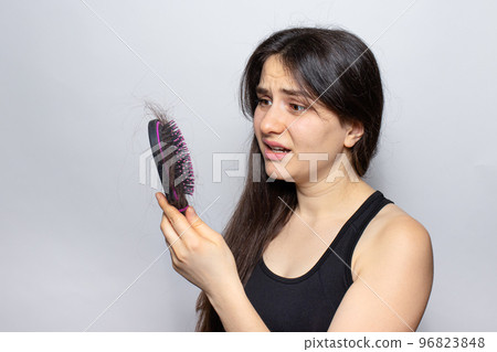 The girl holds a comb for hair with fallen hair. Hair loss, hair care. The girl holds a comb for hair with fallen hair. Hair loss, hair care. 96823848