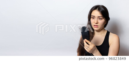 The girl is holding a hairbrush with lost hair. Hair loss, care and treatment. Trichologist, trichology. Banner with place for text copy space 96823849