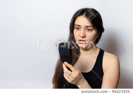 The girl holds a comb for hair with fallen hair. Hair loss, hair care. The girl holds a comb for hair with fallen hair. Hair loss, hair care. 96823850