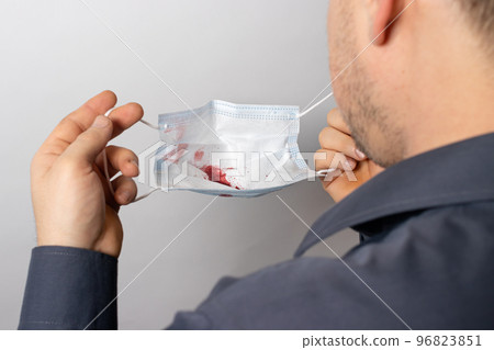 A male patient holds a medical mask with traces of blood. Lung cancer or tuberculosis, pneumonia and hemoptysis A male patient holds a medical mask with traces of blood. Lung cancer or tuberculosis, pneumonia and hemoptysis 96823851