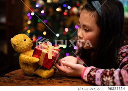 Child receiving a Christmas gift from a teddy bear Child receiving a Christmas gift from a teddy bear 96823854