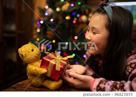 Child receiving a Christmas gift from a teddy bear Child receiving a Christmas gift from a teddy bear 96823855
