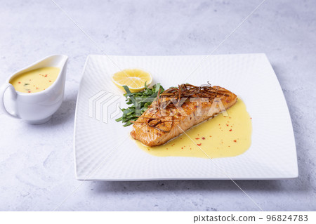 Salmon with beurre blanc sauce, spinach and lemon. Garnished with leeks. Traditional French dish. Close-up. Salmon with beurre blanc sauce, spinach and lemon. Garnished with leeks. Traditional French dish. Close-up. 96824783