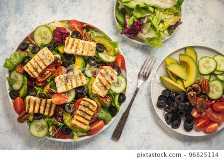 Greek style cuisine - salad with grilled halloumi cheese, avocado, pecan nuts and tomatoes. 96825114