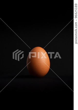 Single egg standing on a black background Single egg standing on a black background 96825189