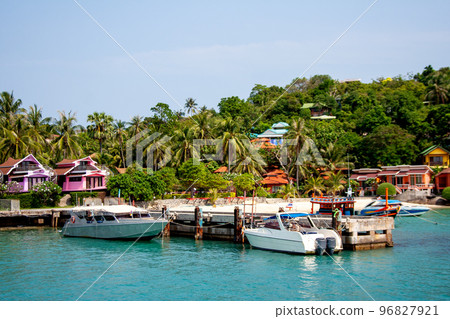 Koh Phangan waterfront with boats near dock, colorful bungalow houses and palms Koh Phangan waterfront with boats near dock, colorful bungalow houses and palms 96827921