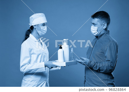 doctor applying antibacterial spray on patient hands on blue background 96828864