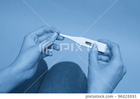 Woman looking at thermometer. Female hands holding a digital thermometer. Concept of fever, flue or virus 96828891