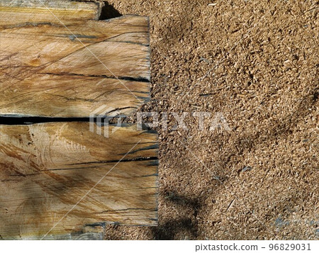 natural brown background of an old dry wood texture with streaks of cracks in the foreground and a texture space of small sawdust in the background in pleasant sunlight natural brown background of an old dry wood texture with streaks of cracks in the foreground and a texture space of small sawdust in the background in pleasant sunlight 96829031