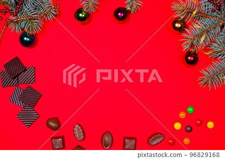 Chocolate and candy on a red background with a spruce sprig for Christmas. A banner with a place for text for a pastry shop. 96829168