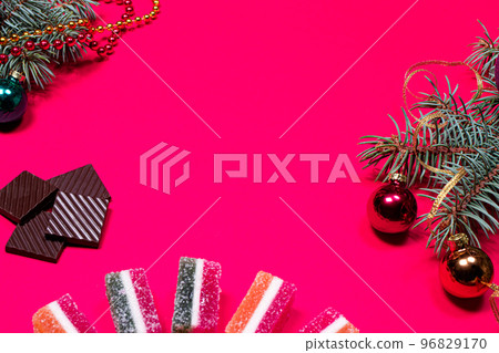 Marmalade jellies and spruce twig with a ribbon and a ball on a pink background. A New year banner for a pastry with a picture of chocolate with a place for copyspace text. Marmalade jellies and spruce twig with a ribbon and a ball on a pink background. A New year banner for a pastry with a picture of chocolate with a place for copyspace text. 96829170