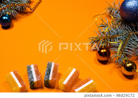 Marmalade jellies and spruce twig with a ribbon and a toy on a yellow background. A banner on a red background with a place for copyspace text. Marmalade jellies and spruce twig with a ribbon and a toy on a yellow background. A banner on a red background with a place for copyspace text. 96829172