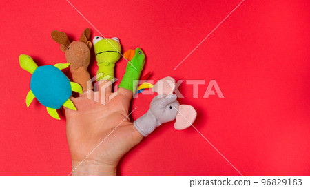 Fingers toys made of fabric on the hand on a red background banner with a place for text. Fingers Theatre. Fingers toys made of fabric on the hand on a red background banner with a place for text. Fingers Theatre. 96829183