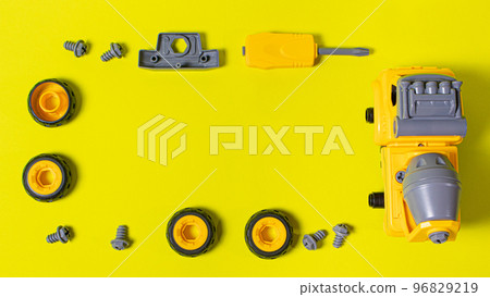 The toy typewriter is a concrete mixer and screwdriver that twists the cog on a yellow background. Photos for a toy store and educational activities. Early development of children. The toy typewriter is a concrete mixer and screwdriver that twists the cog on a yellow background. Photos for a toy store and educational activities. Early development of children. 96829219