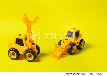 Two toy cars are yellow tractors of lumber loaders. Bright photo for the toy store. 96829220