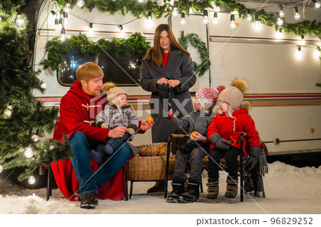 Happy Caucasian family celebrating Christmas outdoors. Parents and three sons travel in a camper. Happy Caucasian family celebrating Christmas outdoors. Parents and three sons travel in a camper. 96829252