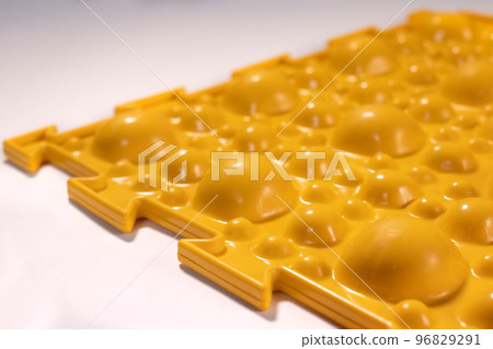Yellow orthopedic mat in the form of small stones on a white background for foot massage. Prevention of children's flat feet Yellow orthopedic mat in the form of small stones on a white background for foot massage. Prevention of children's flat feet 96829291