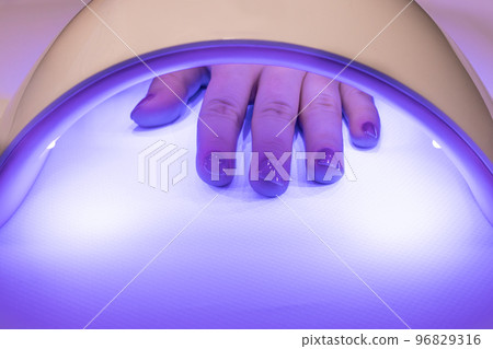 Drying nails with shellac gel polish in a lamp. Nail care at home. UV light, accessories for manicure. 96829316