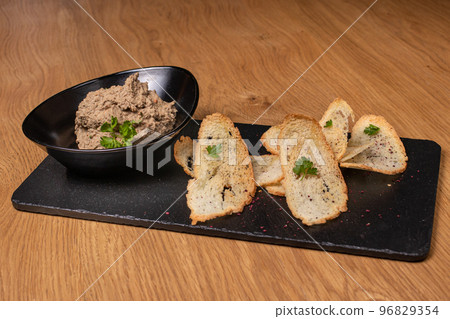 Pate of beef liver and meat with herbs in a black plate with crunchy toast. Restaurant food. Pate of beef liver and meat with herbs in a black plate with crunchy toast. Restaurant food. 96829354