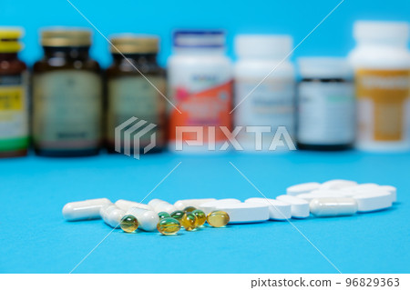 Medicines or dietary supplements on a blue background and jars with pills on the background. Medicines or dietary supplements on a blue background and jars with pills on the background. 96829363