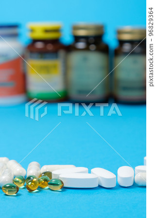 Medicines or dietary supplements on a blue background and jars with pills on the background. Medicines or dietary supplements on a blue background and jars with pills on the background. 96829364