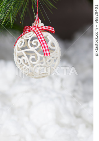 A white Christmas ball and a snow-covered tree branch on a snowy white background. Vertical card place for copy space text 96829401
