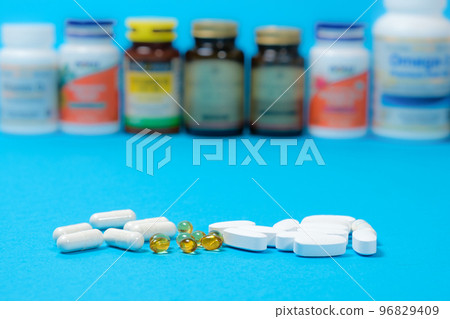 Medicines or dietary supplements on a blue background and jars with pills on the background. Medicines or dietary supplements on a blue background and jars with pills on the background. 96829409