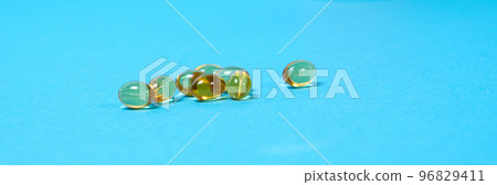 Capsules of vitamin D on a blue background, a long banner with space for text. Vitamins for people Capsules of vitamin D on a blue background, a long banner with space for text. Vitamins for people 96829411