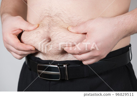 The man shows belly fat. Obesity in men, weight loss The man shows belly fat. Obesity in men, weight loss 96829511